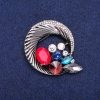 Soldes ! Broche ronde «Bordure» avec strass, qui s'entrelacent dans une belle composition, métal sombre 45×50 mm
